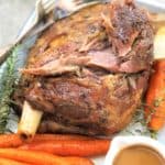 slow cooked pulled lamb shoulder in a white baking dish with carrots