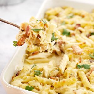 creamy yellow pasta and bacon pieces in a white baking dish