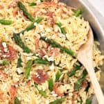 rice shaped pasta with chopped asparagus in a fry pan