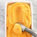 Orange coloured peach sorbet in a white loaf pan
