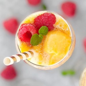 top down view of orange coloured sorbet red raspberries and sparkling wine in a glass