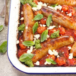baked sausages sitting in a red tomato sauce in a white pan