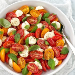 tomatoes bocconcini basil and mint in a white bowl