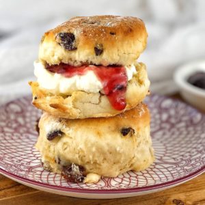 2 scones with jam and cream sitting on a patterned plate