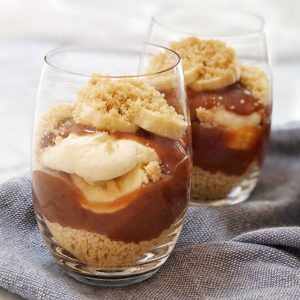 biscuit crumbs caramel cream and sliced banana in a glass