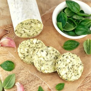 slices of compound butter and basil leaves on a bread board