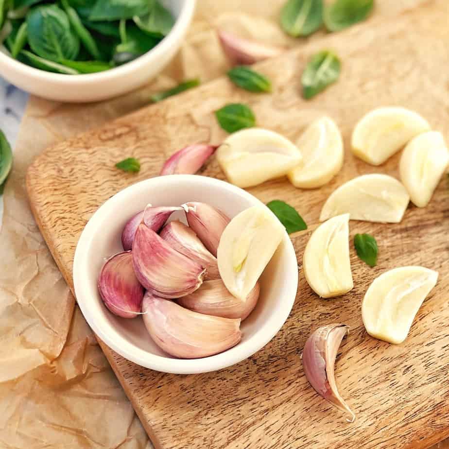 garlic cloves and basil leaves on a chopping board