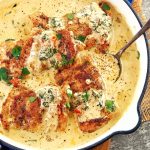 fried chicken thighs sitting in a cream sauce in a pan