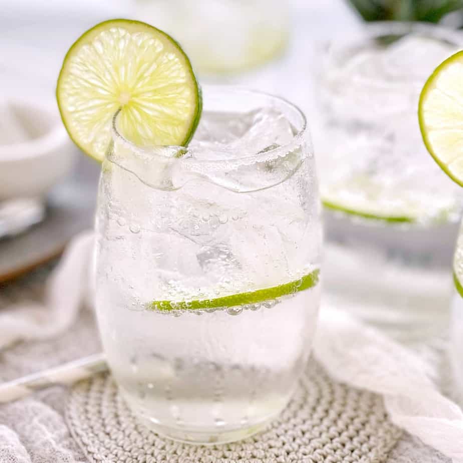 clear drink in a clear glass with a slice of lime on the side