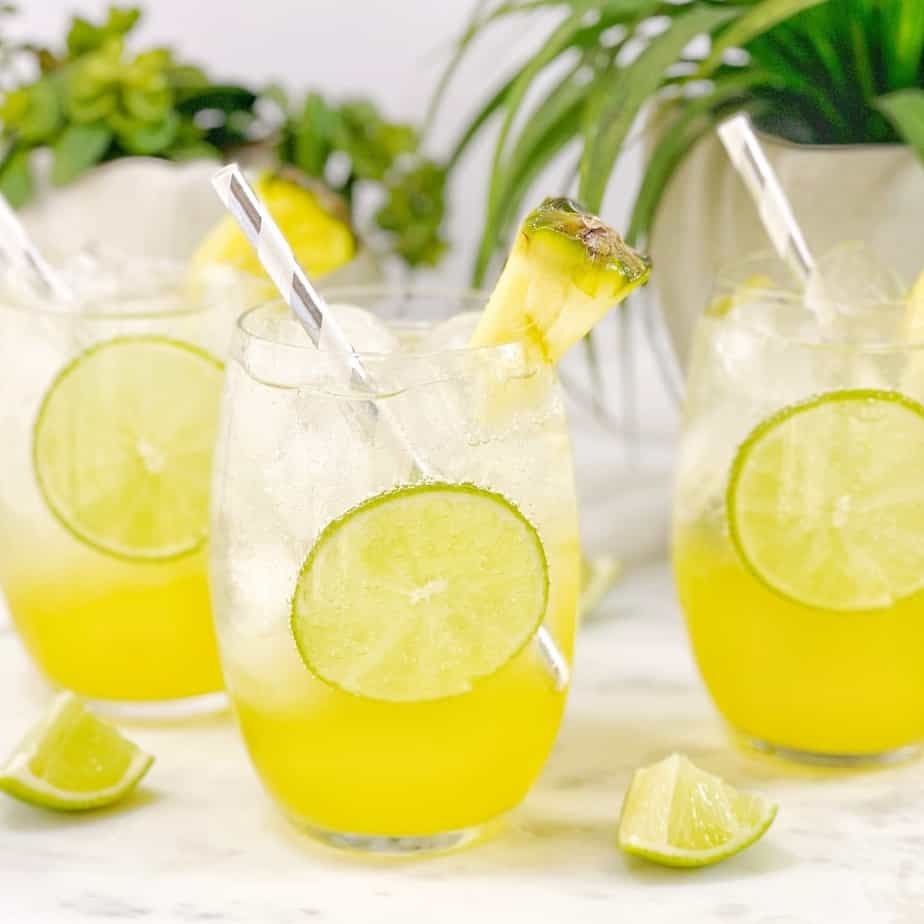 a clear and yellow layered drink with a piece of lime in a clear glass