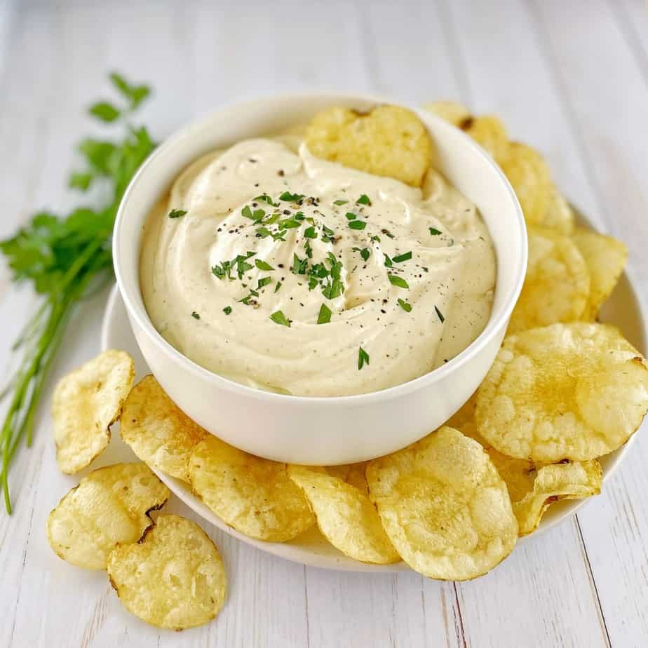 sour cream dip in a white bowl with chips around the base