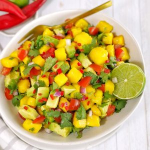chopped fresh mango salsa in a white bowl with chillies and a spoon