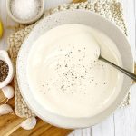 truffle aioli in a white bowl on a wooden board with a spoon