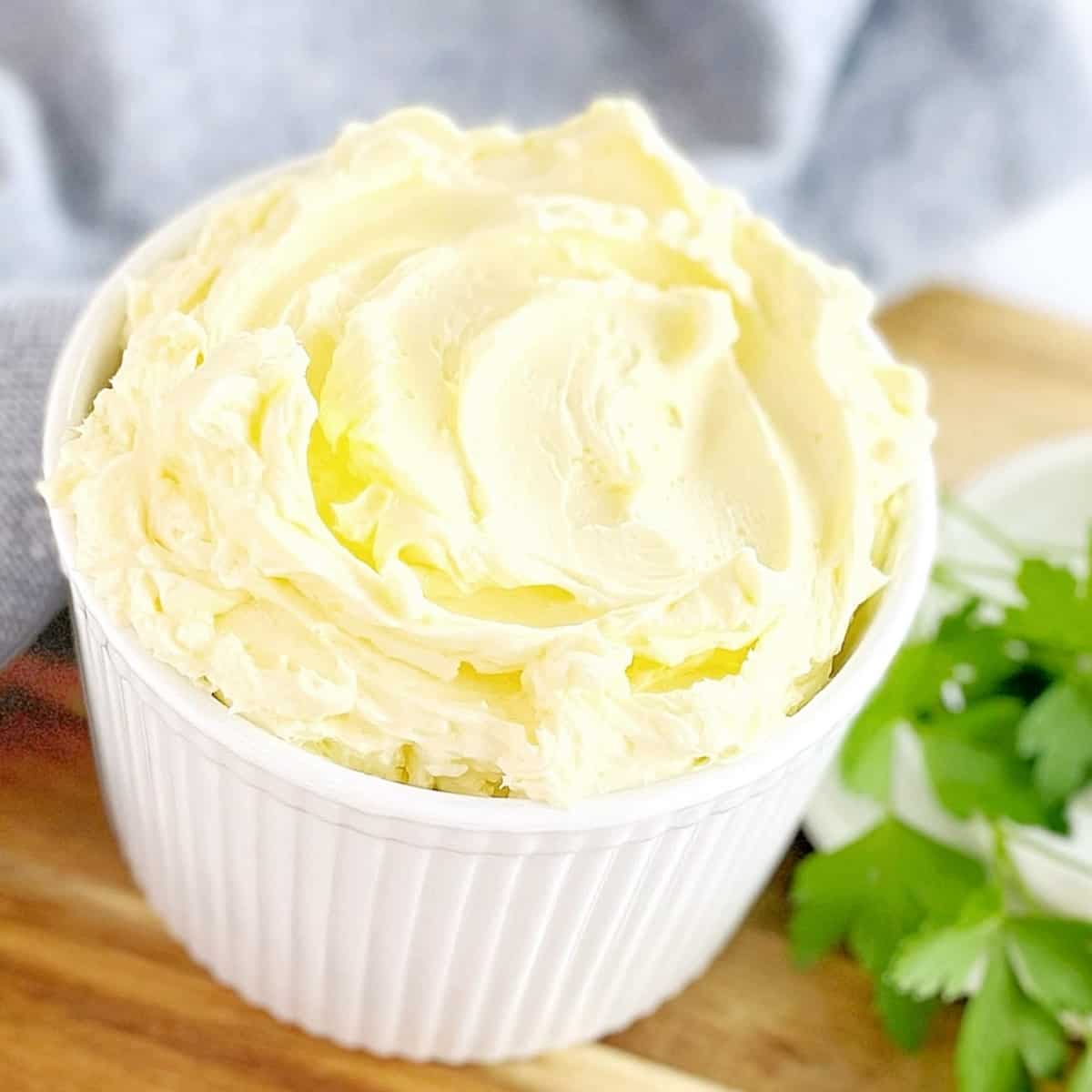 white ramekin filled with whipped butter on a wooden board with parsley