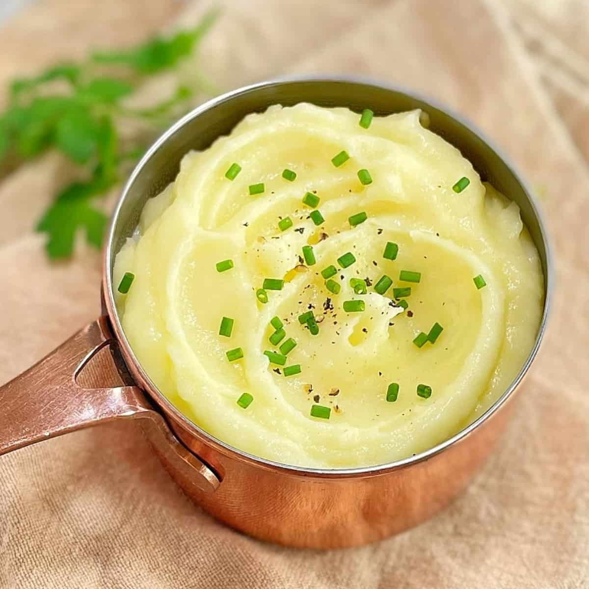 pomme puree in a copper pot with chives on top