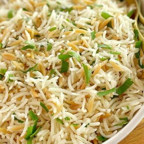 basmati rice and orzo pasta in a white bowl with parsley and spoons