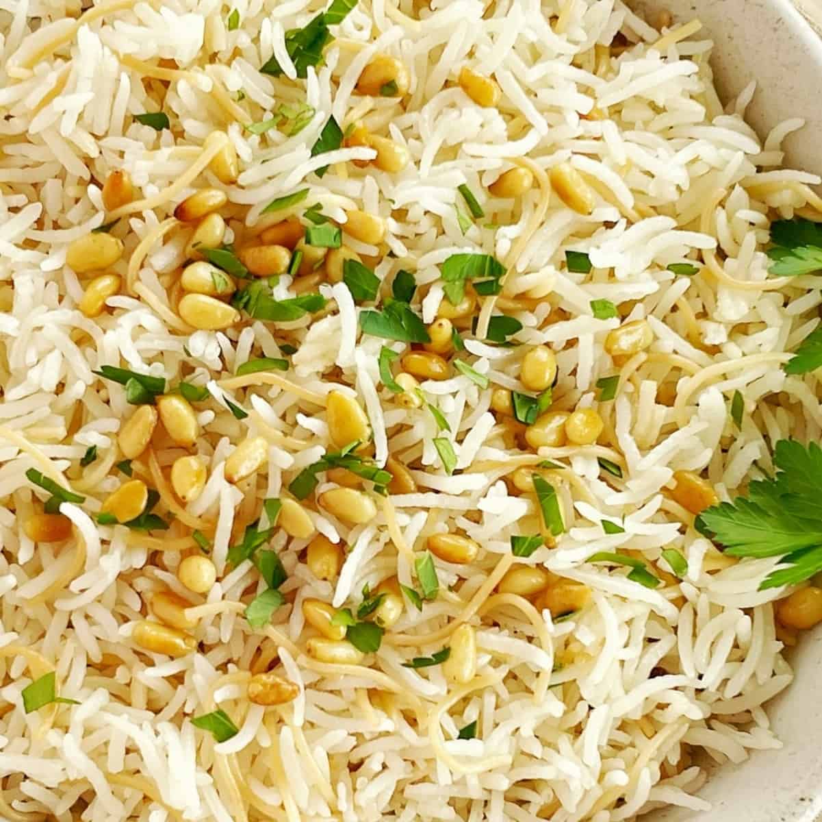 basmati rice with golden fried vermicelli pasta in white bowl with pine nuts and parsley