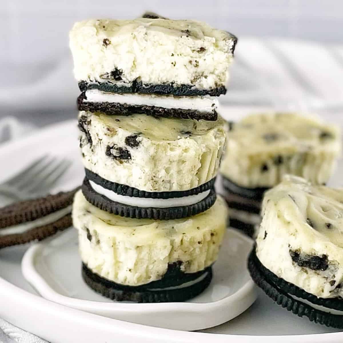 a stack of individual oreo cheesecakes on a white plate with a fork