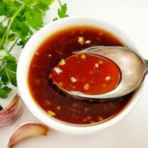 honey sriracha dipping sauce in a small white bowl with a spoon.