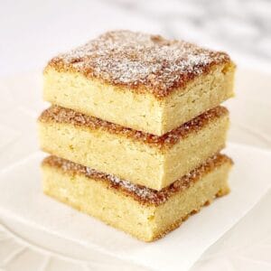 Three square pieces of snickerdoodle flavoured bars stacked on a white plate.