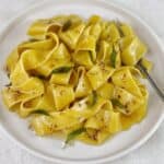 Pasta with butter sauce and crispy sage leaves on a white plate with a fork.