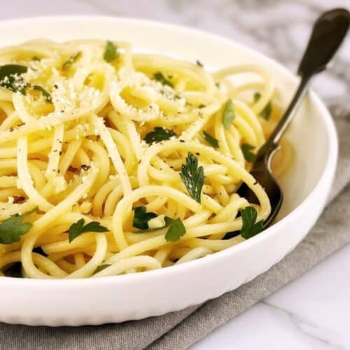 Lemon pasta in a white bowl with parsley and a fork.