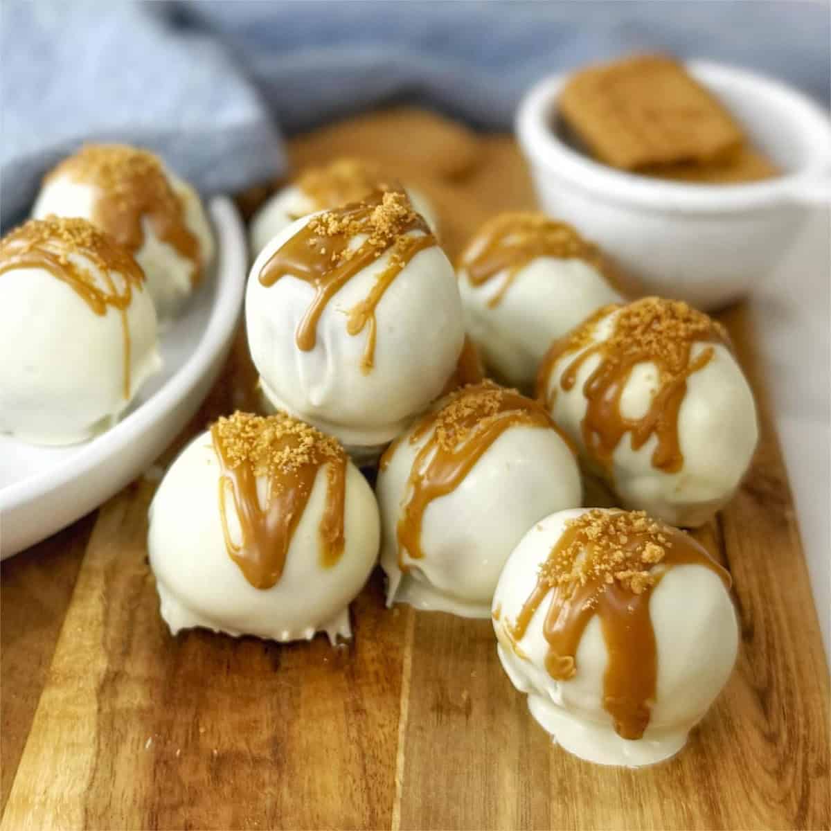 Biscoff truffle balls sitting on a wooden board with a white plate.