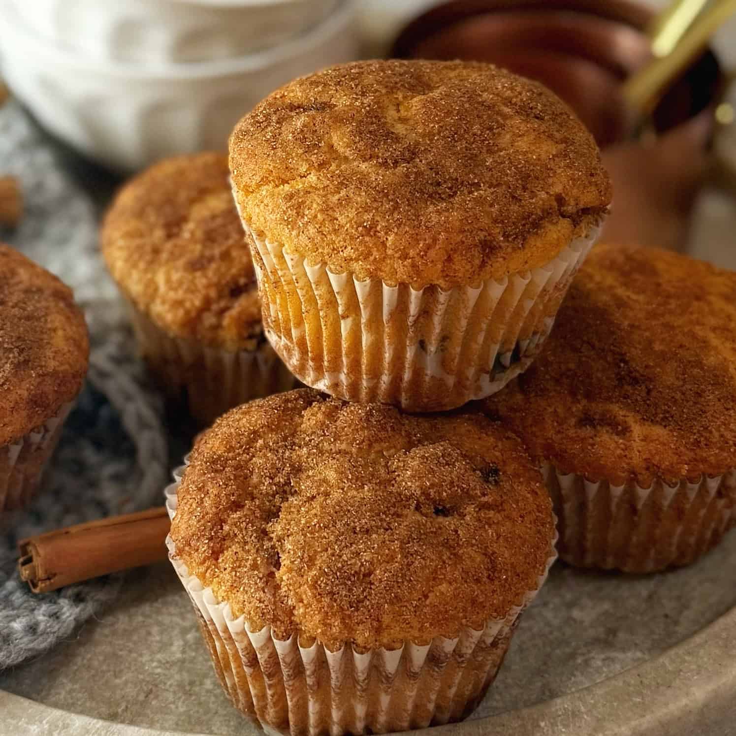 Raisin muffins on a tray with cinnamon sticks.
