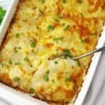 Creamy potato bake in a white baking dish with a spoon.