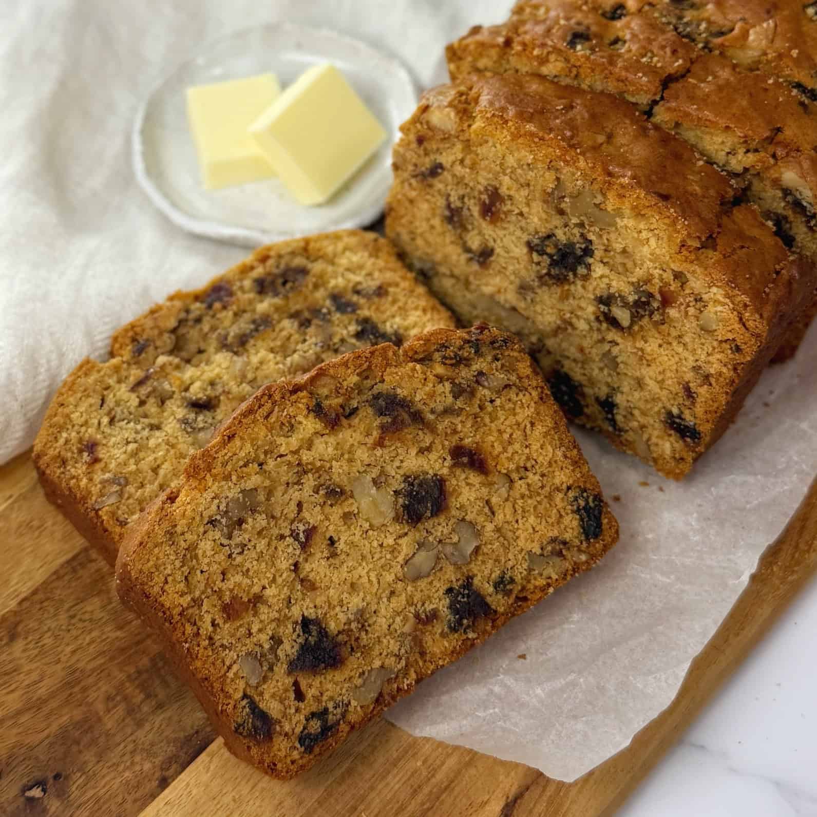 Slices of date and walnut loaf on a wooden board.