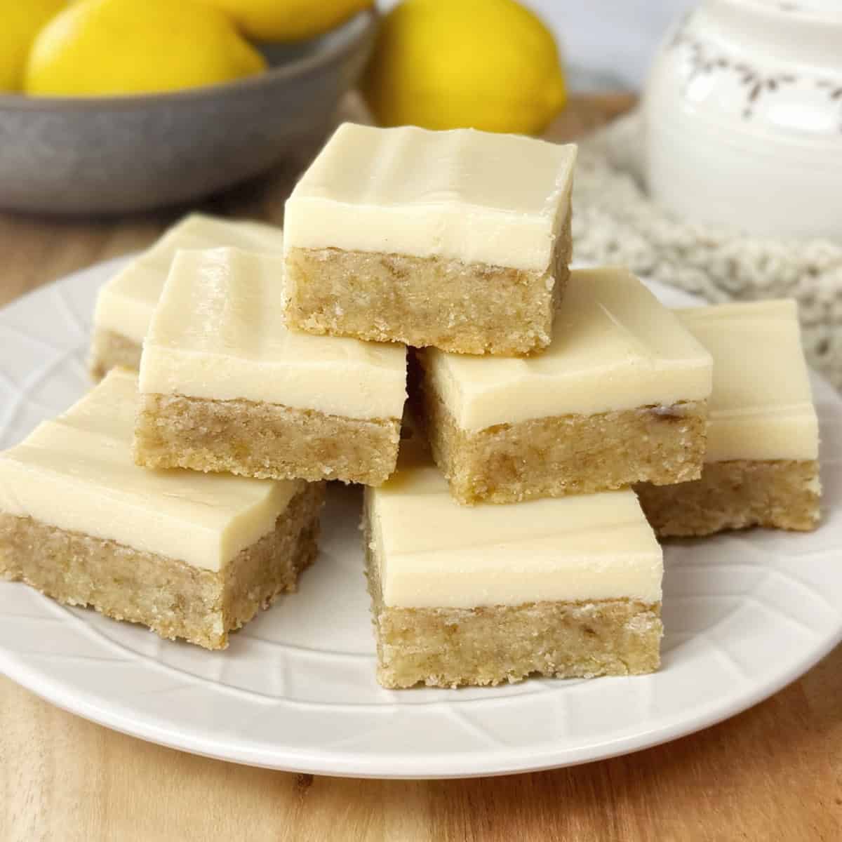 Pieces of slice on a white plate with lemons in the background.